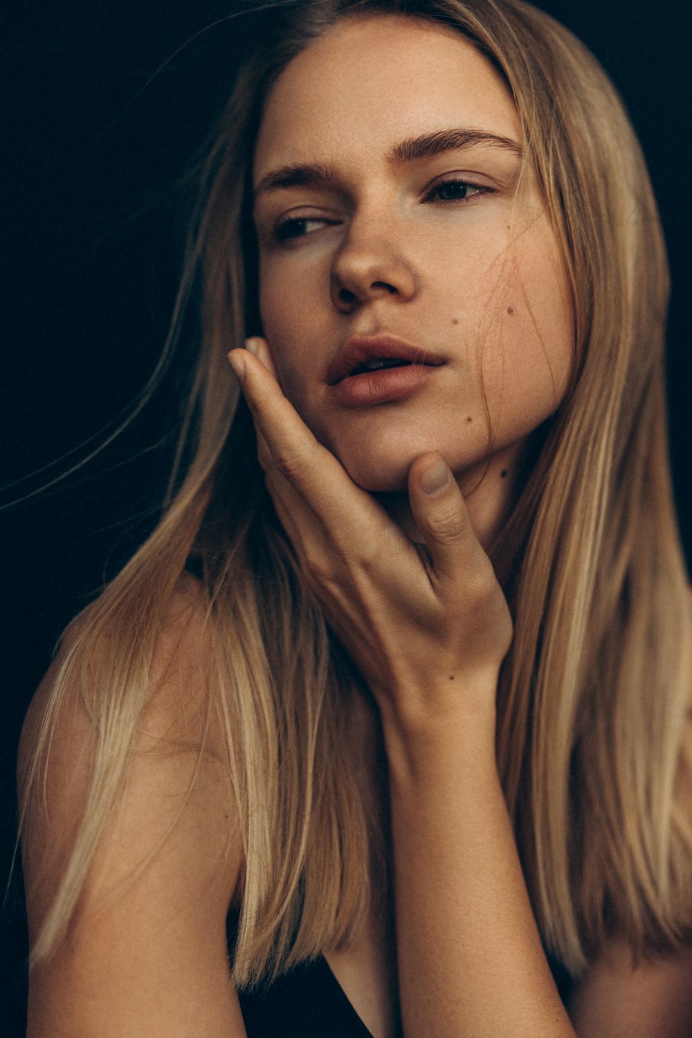 Woman touching her face with soft expression.