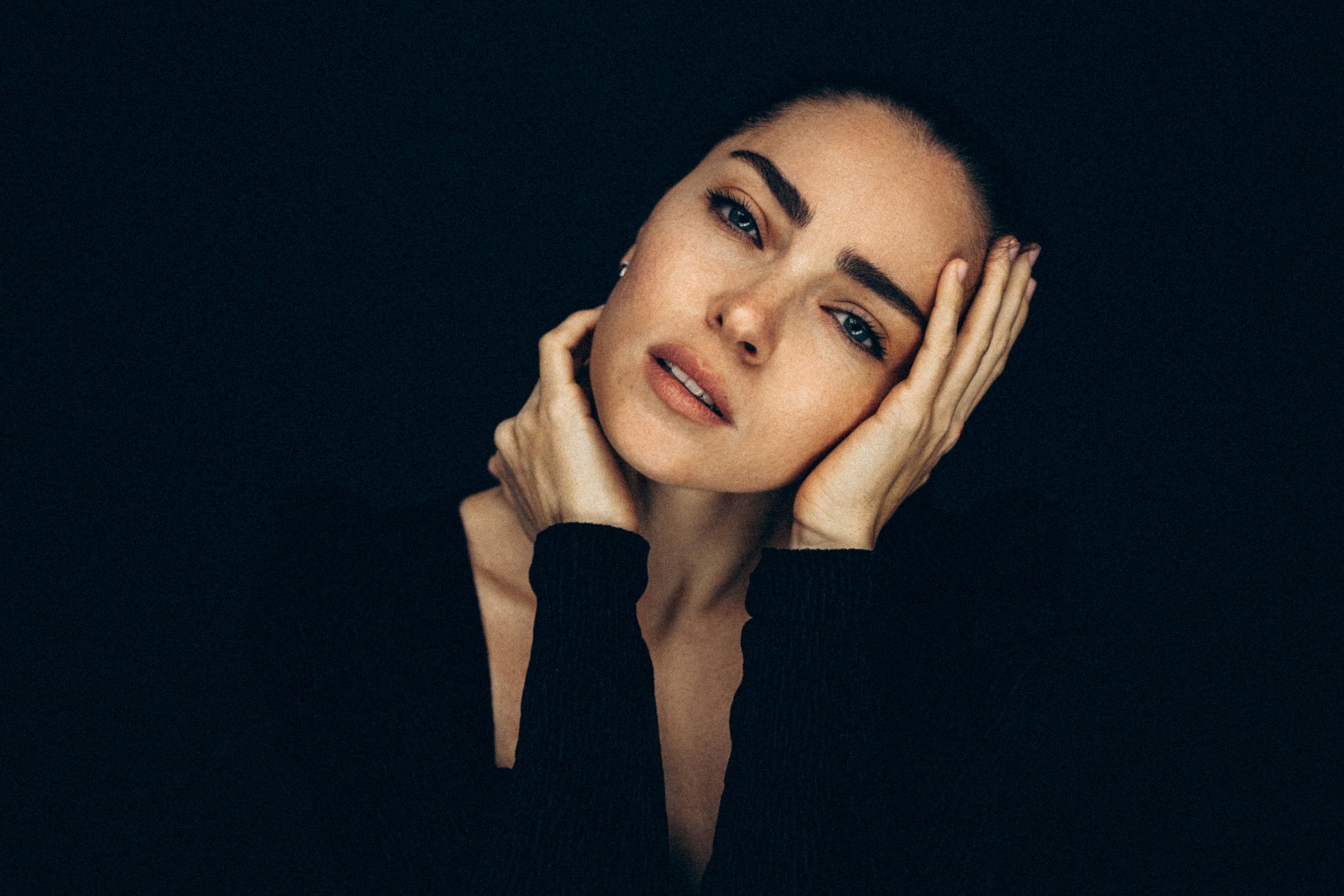 Woman with hands on face against dark background