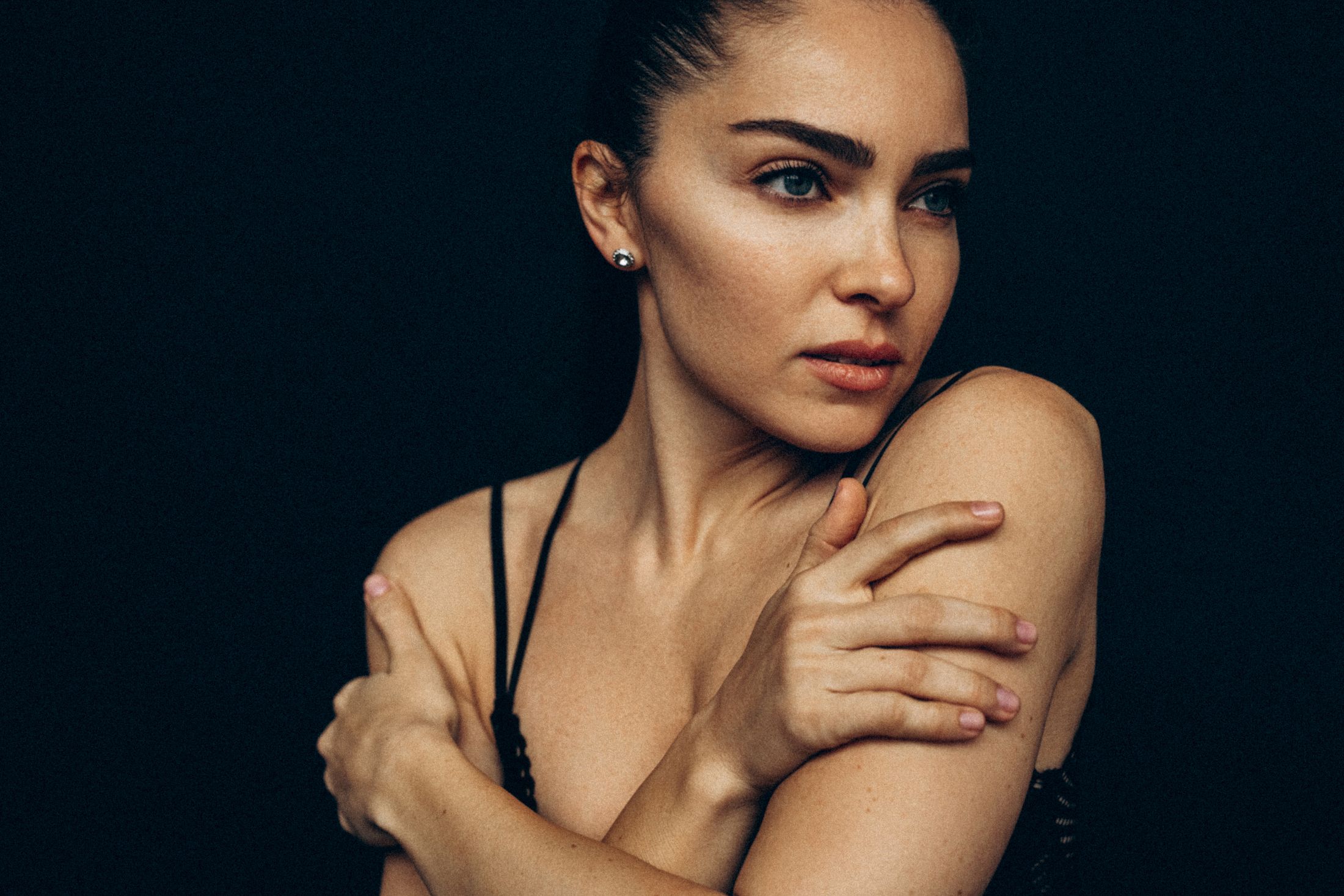 Woman posing gracefully with a dark background.